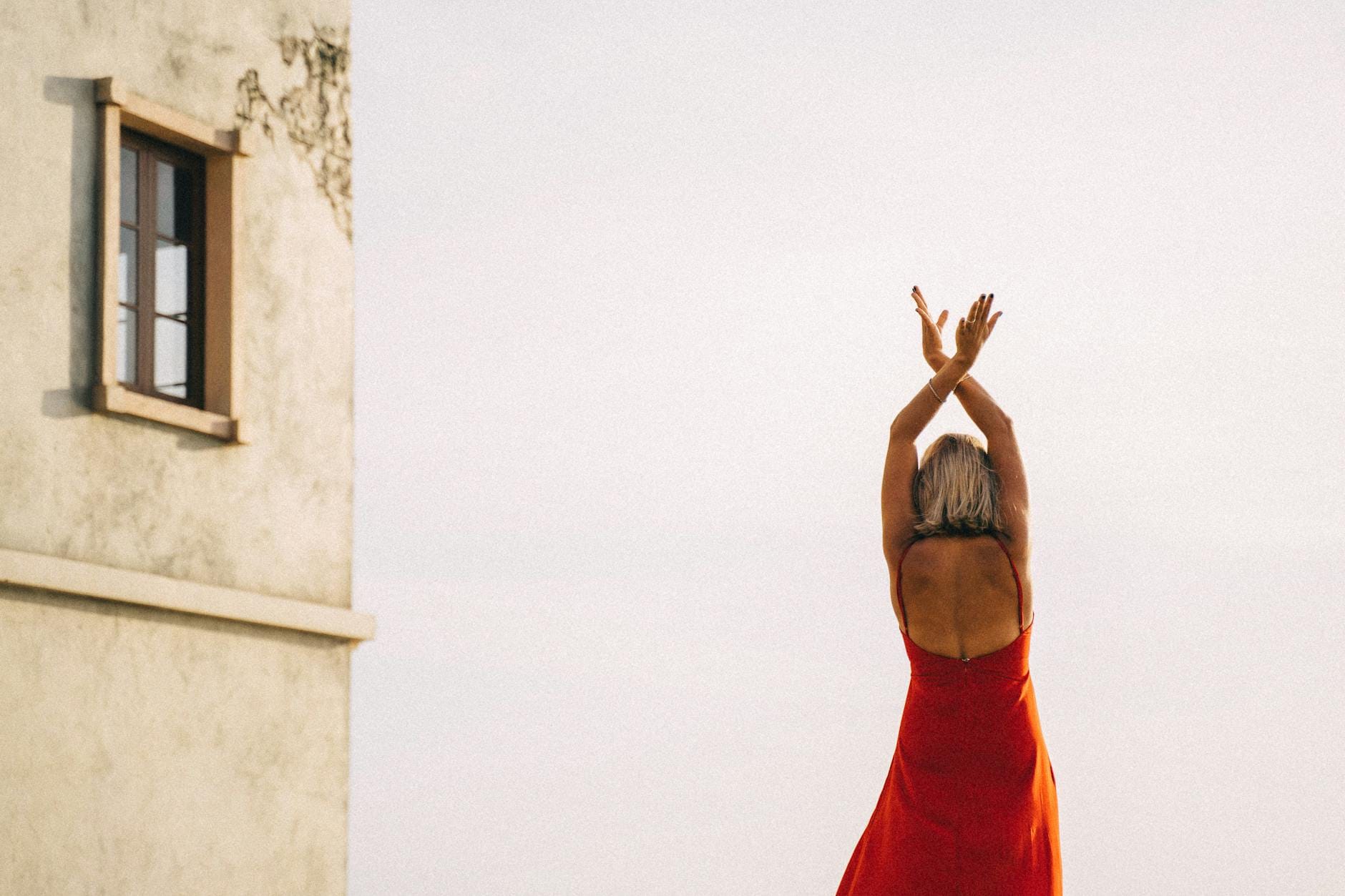 Kobieta w czerwonej sukience tańczy salsę na zewnątrz budynku